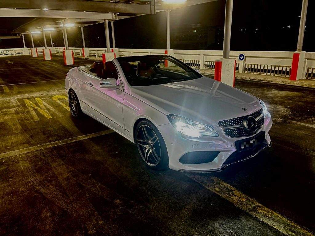 White Mercedes E-Class cabriolet with the roof folded away on a bright Singapore afternoon